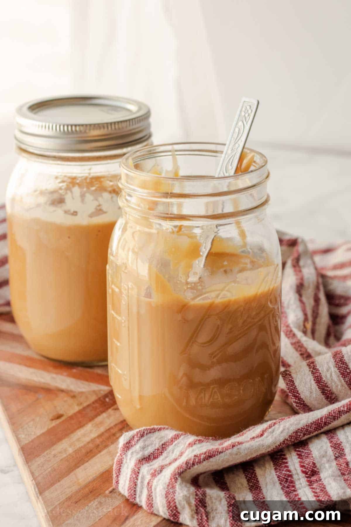 Easy Instant Pot Dulce De Leche 6 An open glass jar of freshly cooked dulce de leche in the Instant Pot, with a metal spoon, showcasing the warm, creamy caramel.