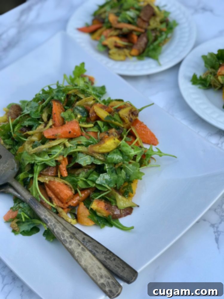 A beautifully arranged serving of Roasted Carrot and Fennel Salad, featuring fresh arugula and a luscious dressing