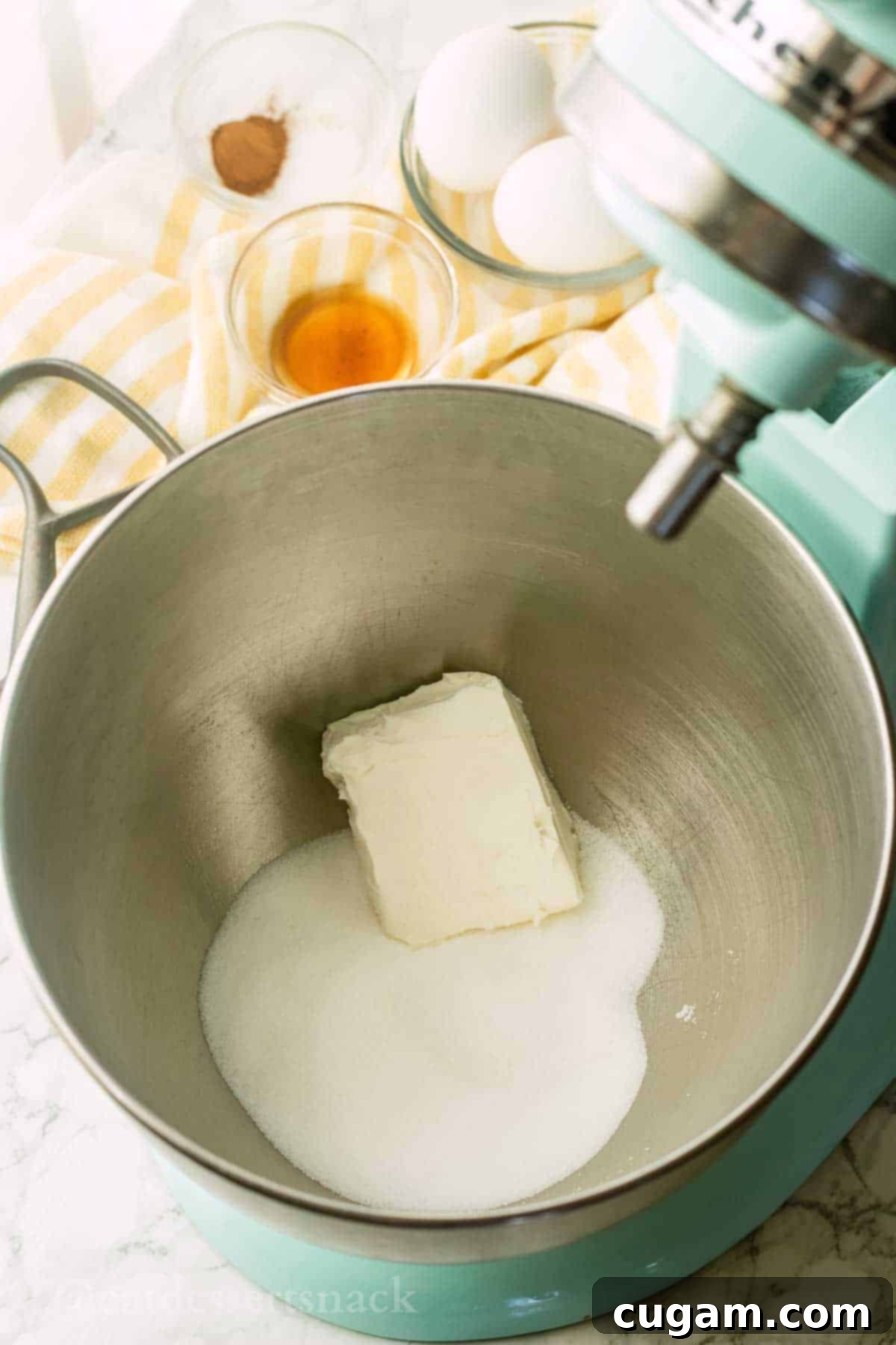 Cream cheese and white granulated sugar in metal mixing bowl.