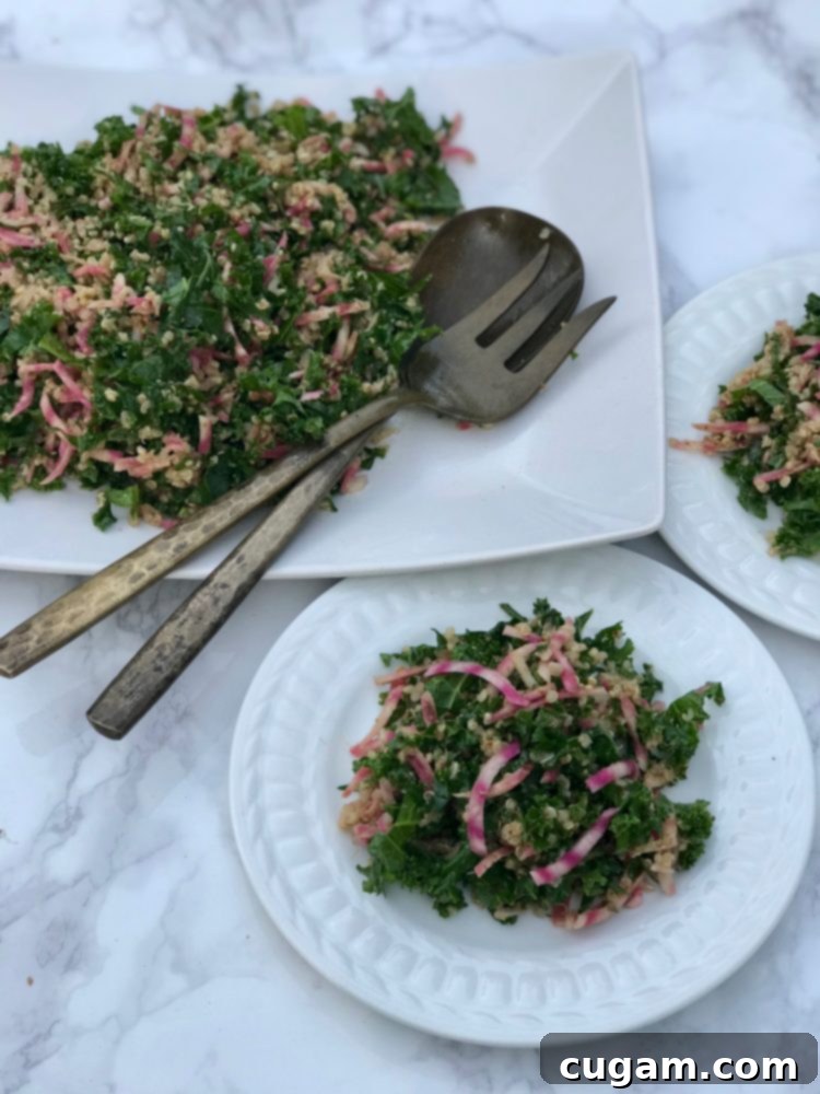 A close-up of the finished kale salad, highlighting the shredded kale, candy cane beets, quinoa, and spiced pecans for a delicious combination.