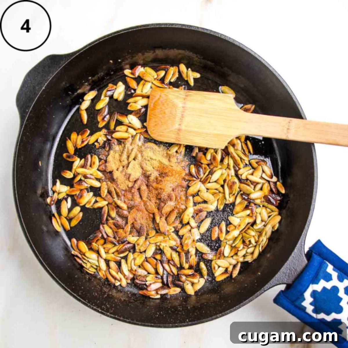 Toasted pumpkin seeds in a cast iron skillet with spices sprinkled onto the center.