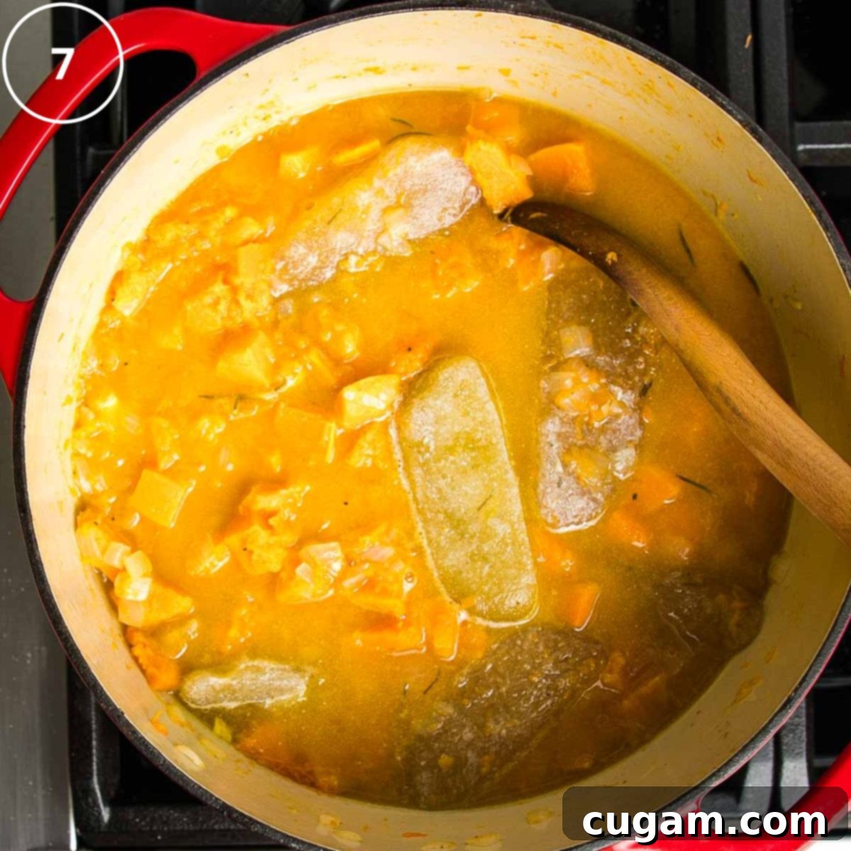 Butternut squash soup with cubes of stock floating in dutch oven with roasted veggies.