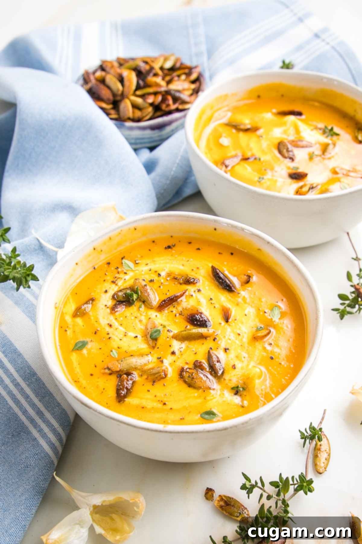 Bowl of creamy butternut squash soup with a swirl of sour cream and some toasted pepitas. 