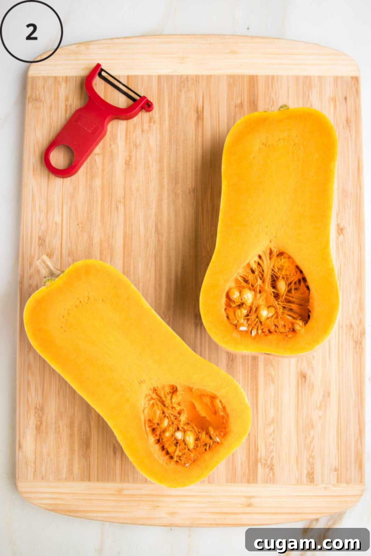 Butternut squash halved lengthwise, flesh side up on a cutting board.