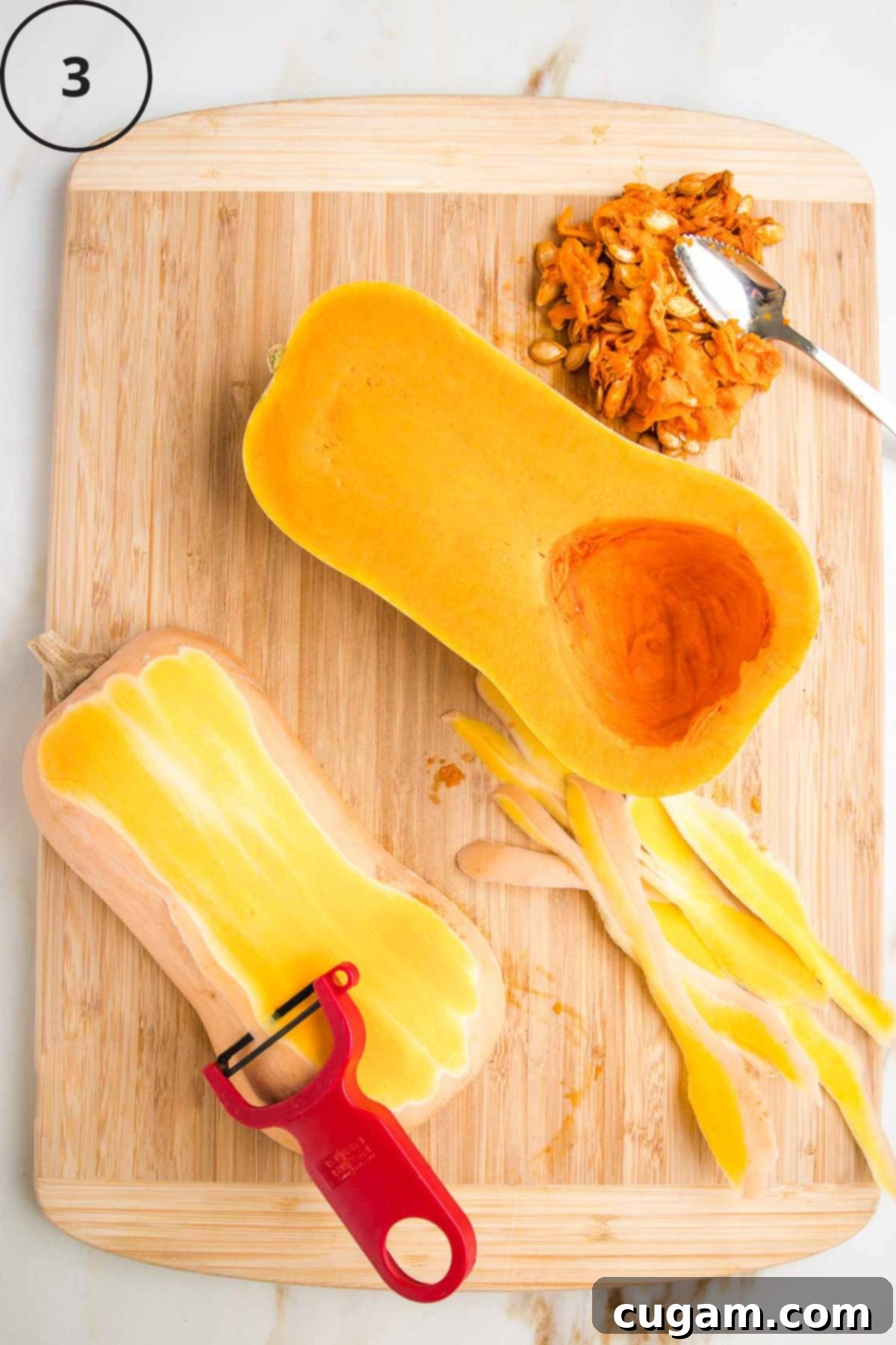 Butternut squash, halved, seeds scooped out and now being peeled by a "Y" vegetable peeler.