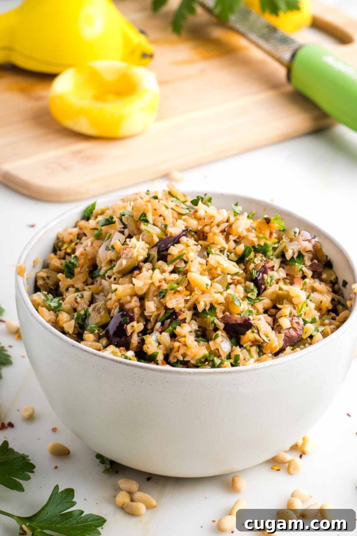 Vibrant Mediterranean Cauliflower Rice 2 Cauliflower Rice with olives, pine nuts and fresh parsley, with lemon in the background.
