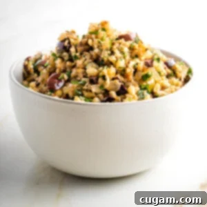 Cauliflower rice with olives, pine nuts and parsley in a white bowl.