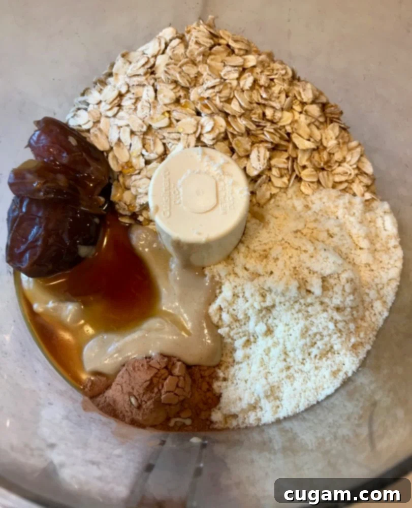 Ingredients in the bowl of food processor:  rolled oats, dates, tahini, almond flour, cacao powder, maple syrup.