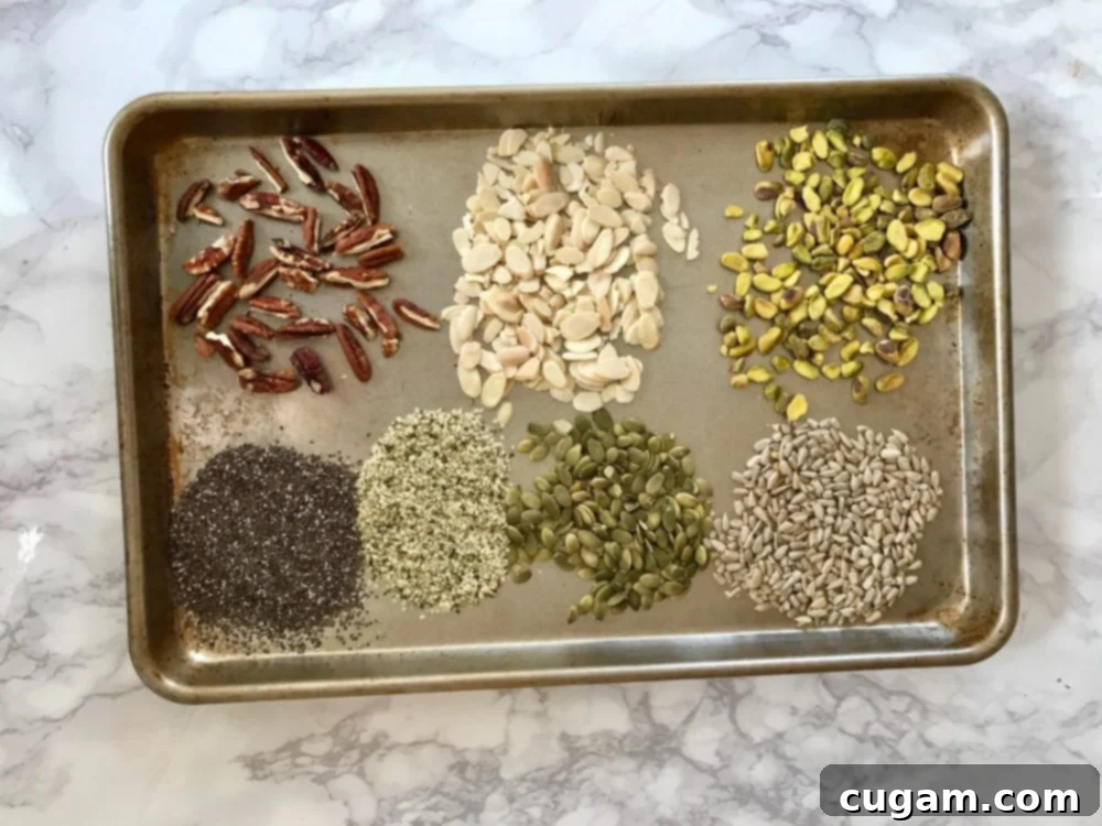 Small sections of nuts and seeds on a rimmed baking sheet. Pecans, almonds, pistachios, pepitas, sunflower seeds, chia seeds, hemp seeds. 