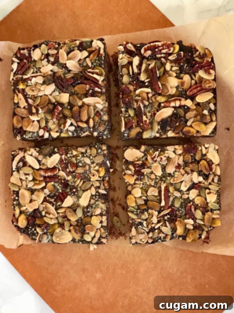 Close-up of freshly cut chocolate oatmeal trail bars, showcasing the dense oatmeal base, thick chocolate layer, and abundant trail mix topping.