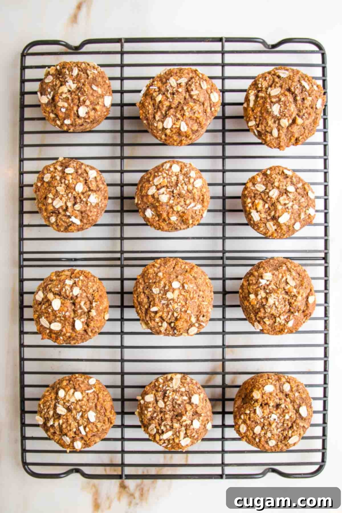 A dozen golden-brown oatmeal muffins, fresh from the oven, cooling on a wire rack, ready to be enjoyed.