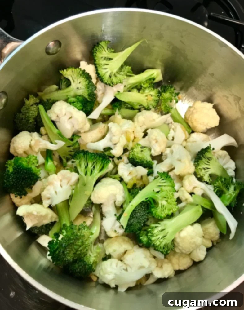 Heartier vegetables like broccoli and cauliflower being added to a pot for miso soup.