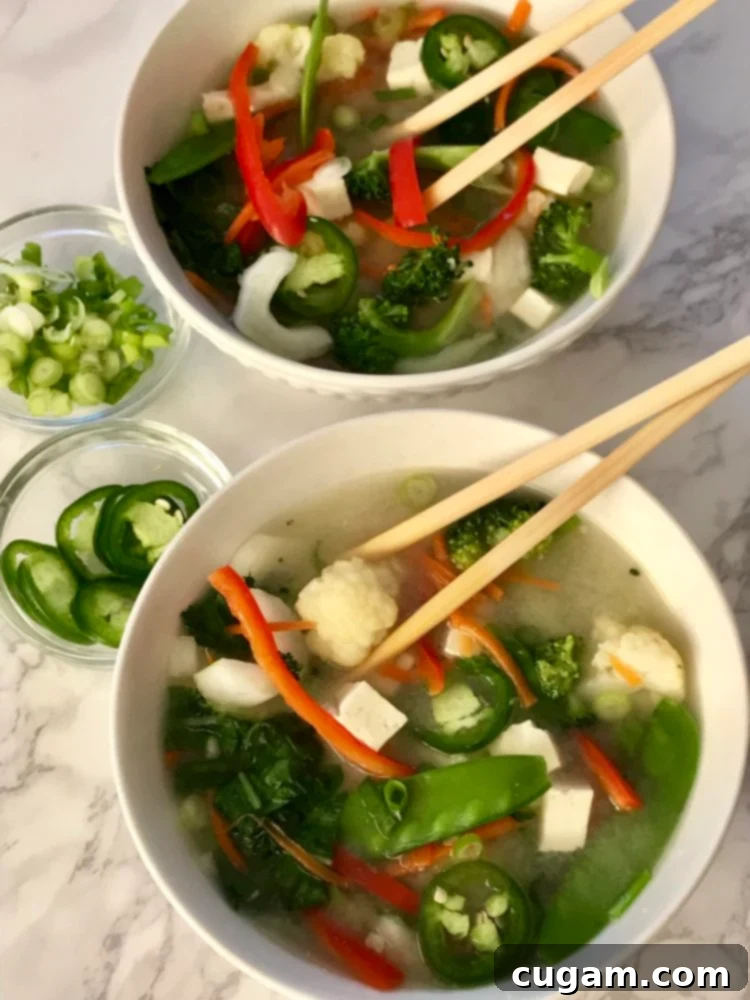 Miso soup with tofu and chunky vegetables in a bowl, garnished with scallions.