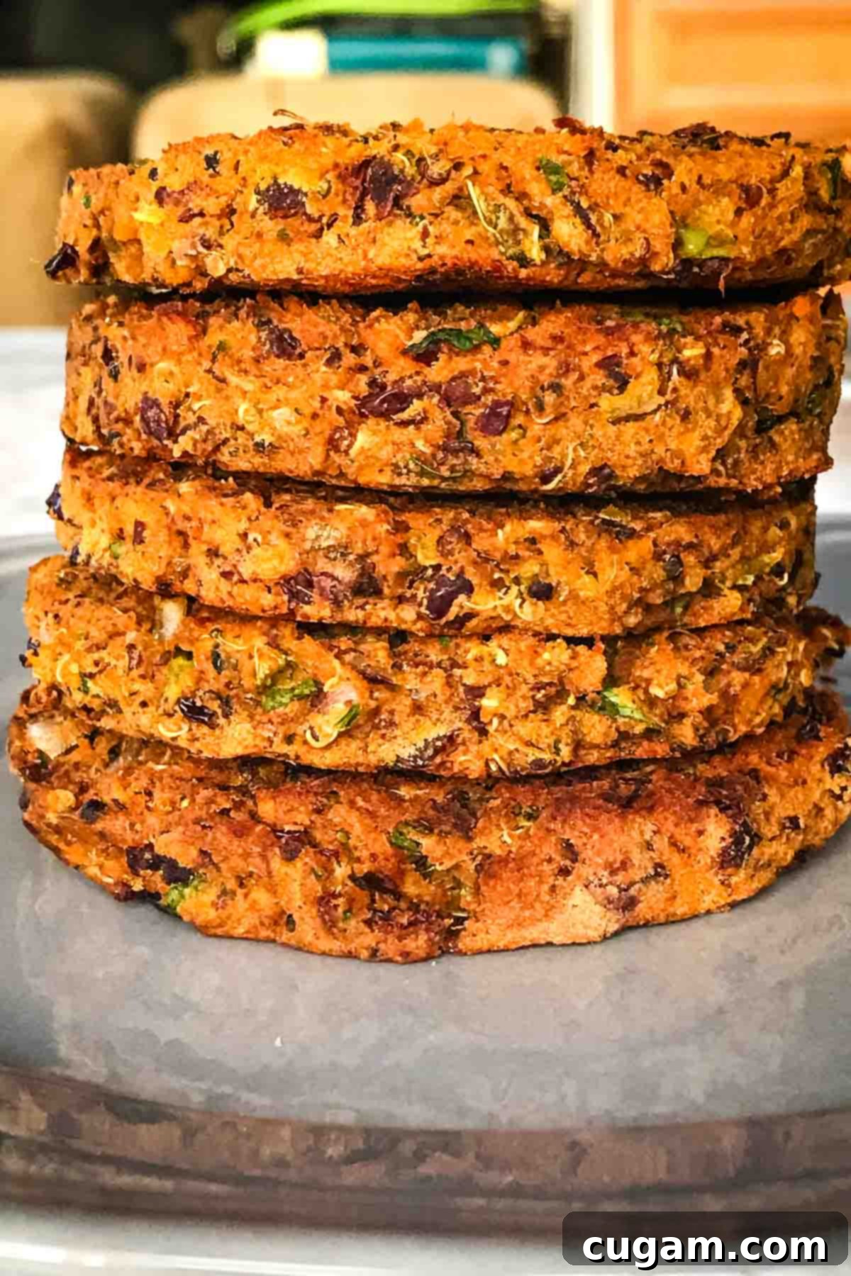 Four sweet potato black bean burgers cooking in a pan, with fresh ingredients in the background.
