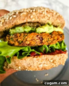 Veggie burger in a bun with lettuce, ketchup and guacamole.