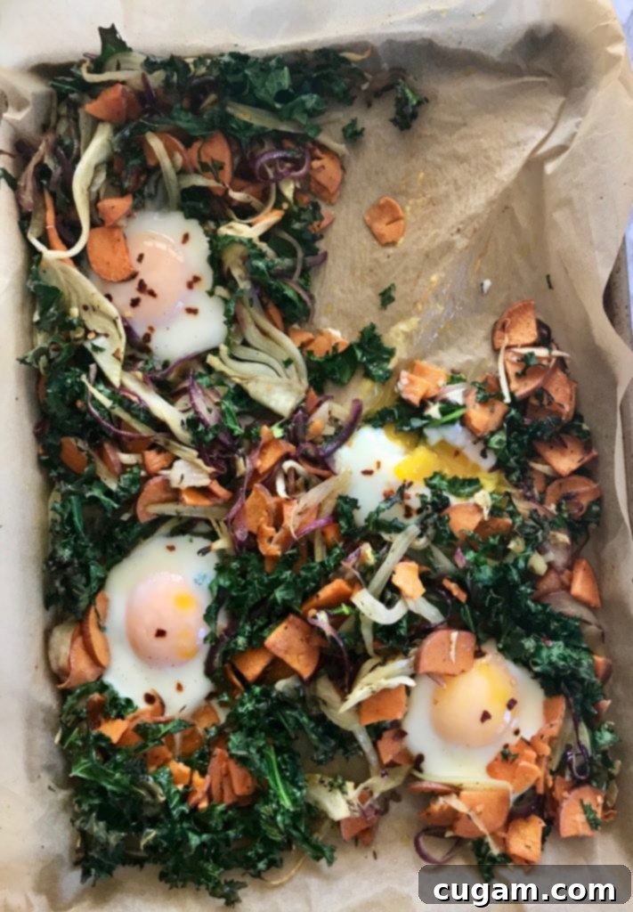 Parchment lined baking tray with veggie hash and cooked eggs. 
