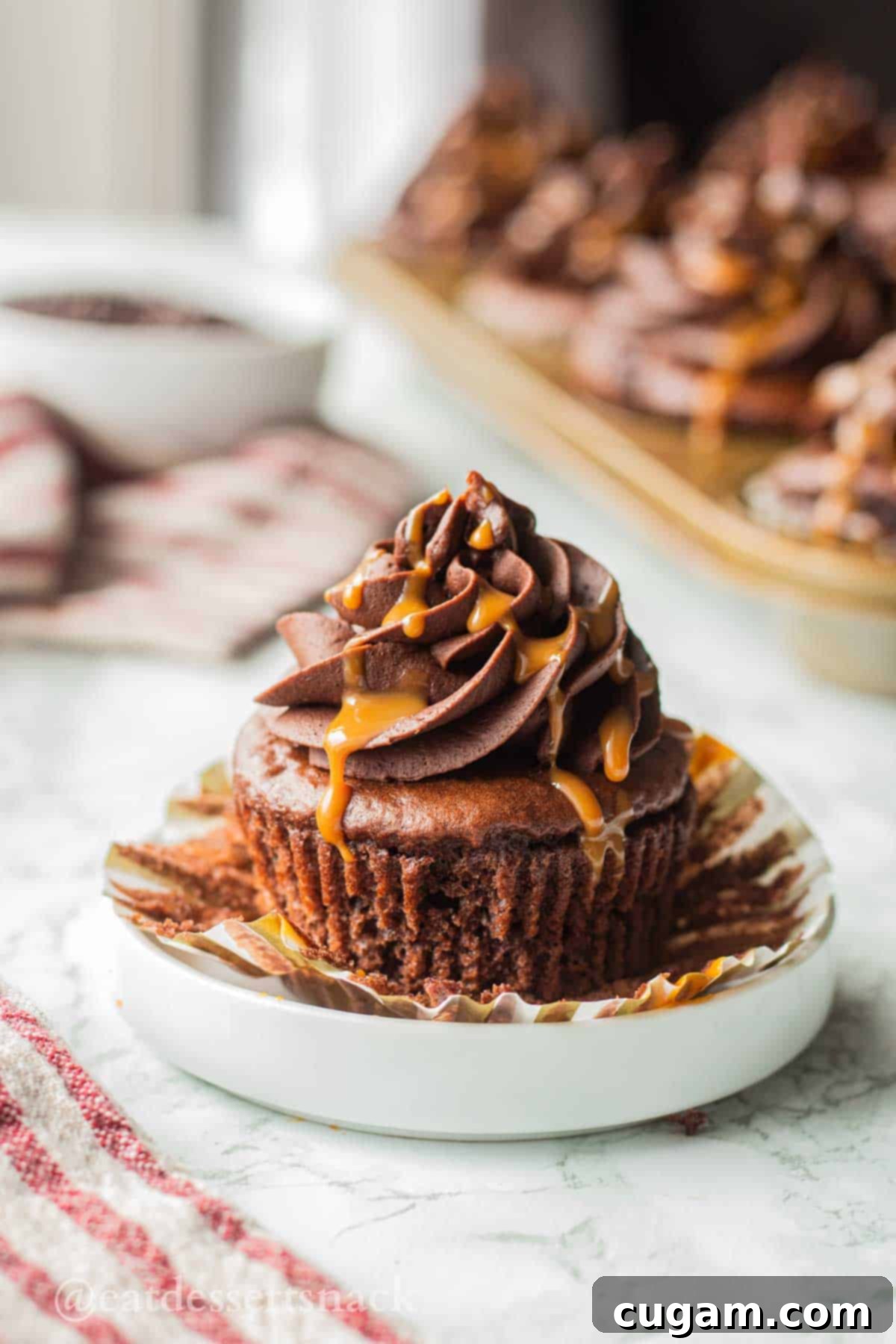 Decadent Chocolate Caramel Cupcakes 2 Unwrapped chocolate cupcake with frosting and caramel drizzle on top, showcasing the rich chocolate and dulce de leche.