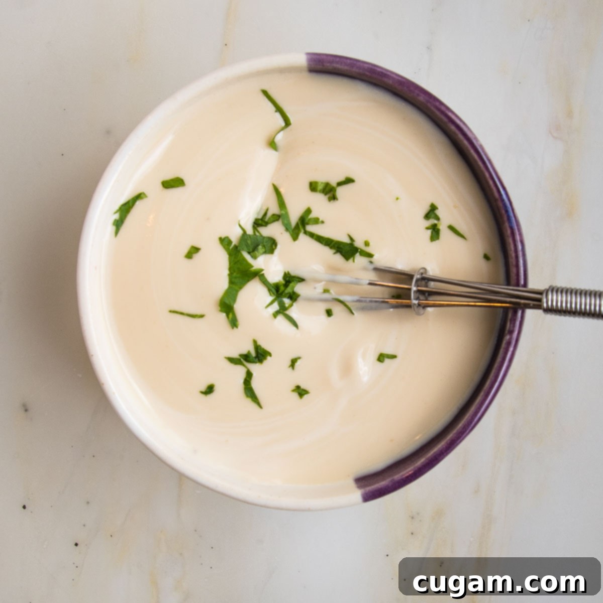 small bowl with tahini sauce, sprinkled with fresh parsley