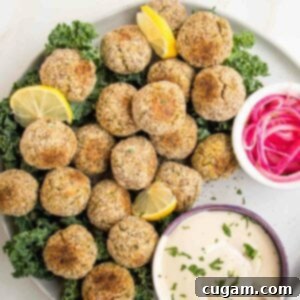 plate filled with baked falafel balls, tahini sauce and small bowl of pickled onions.