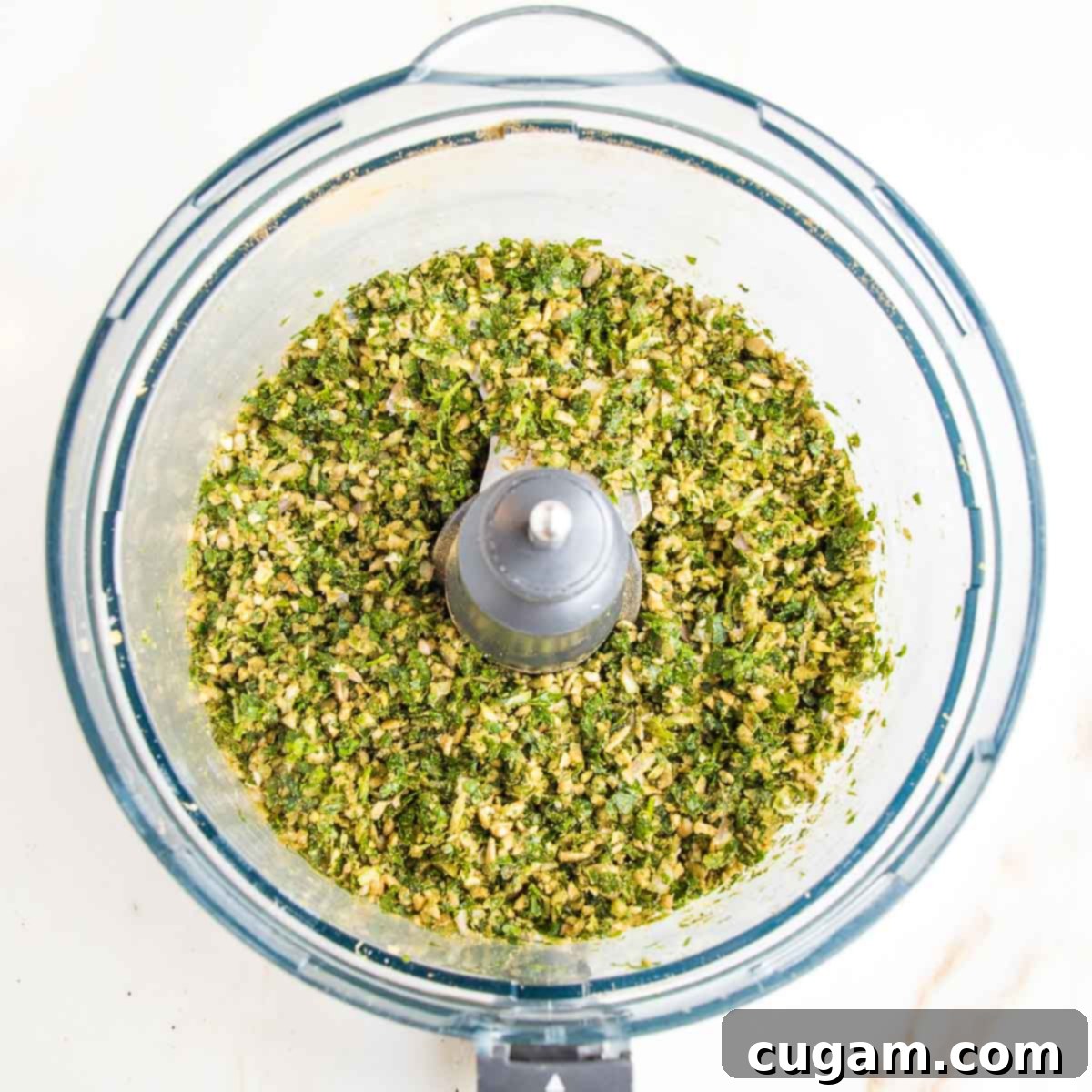 Ground herbs, spices, nuts in the bowl of a food processor.
