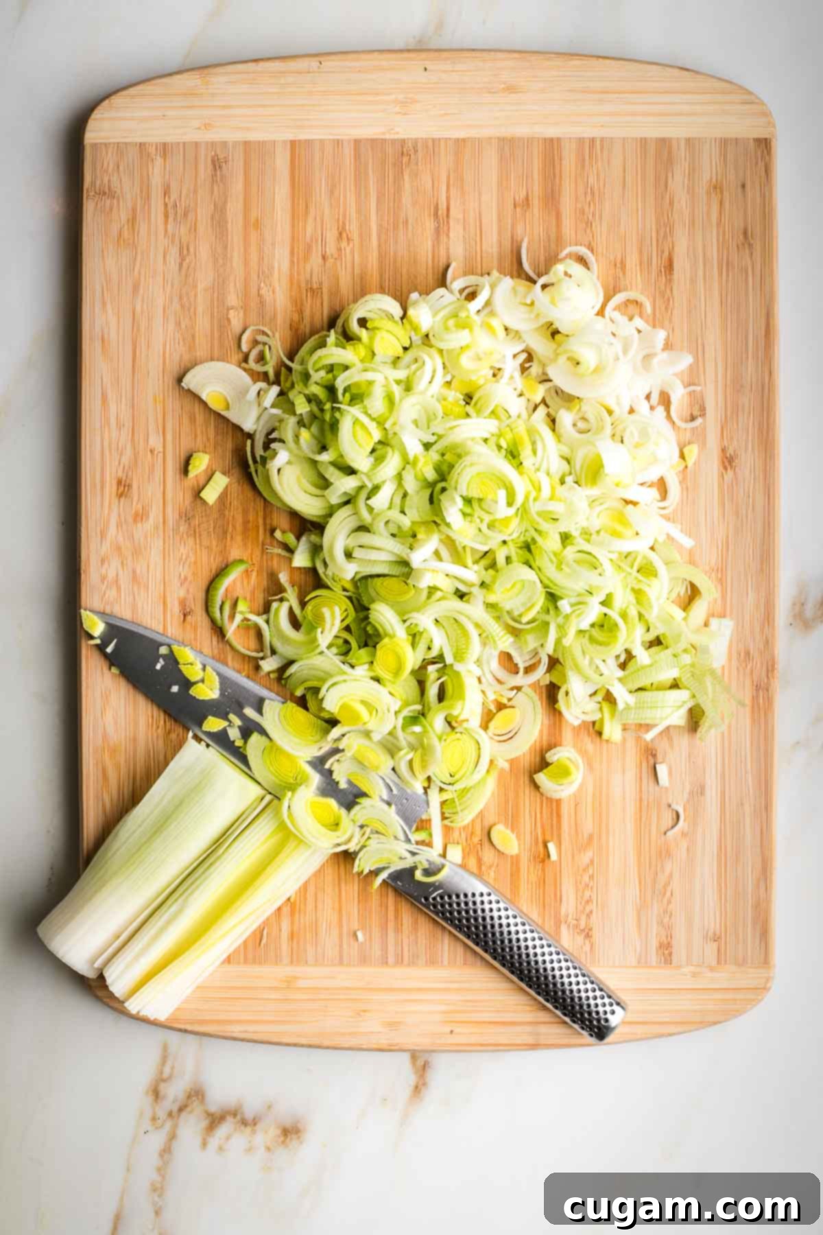 Thinly slicing leeks on a cutting board.