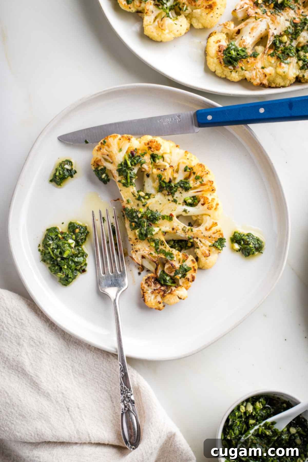 Cauliflower steak on a plate smothered in chimichurri sauce, showcasing its vibrant colors and appealing texture.