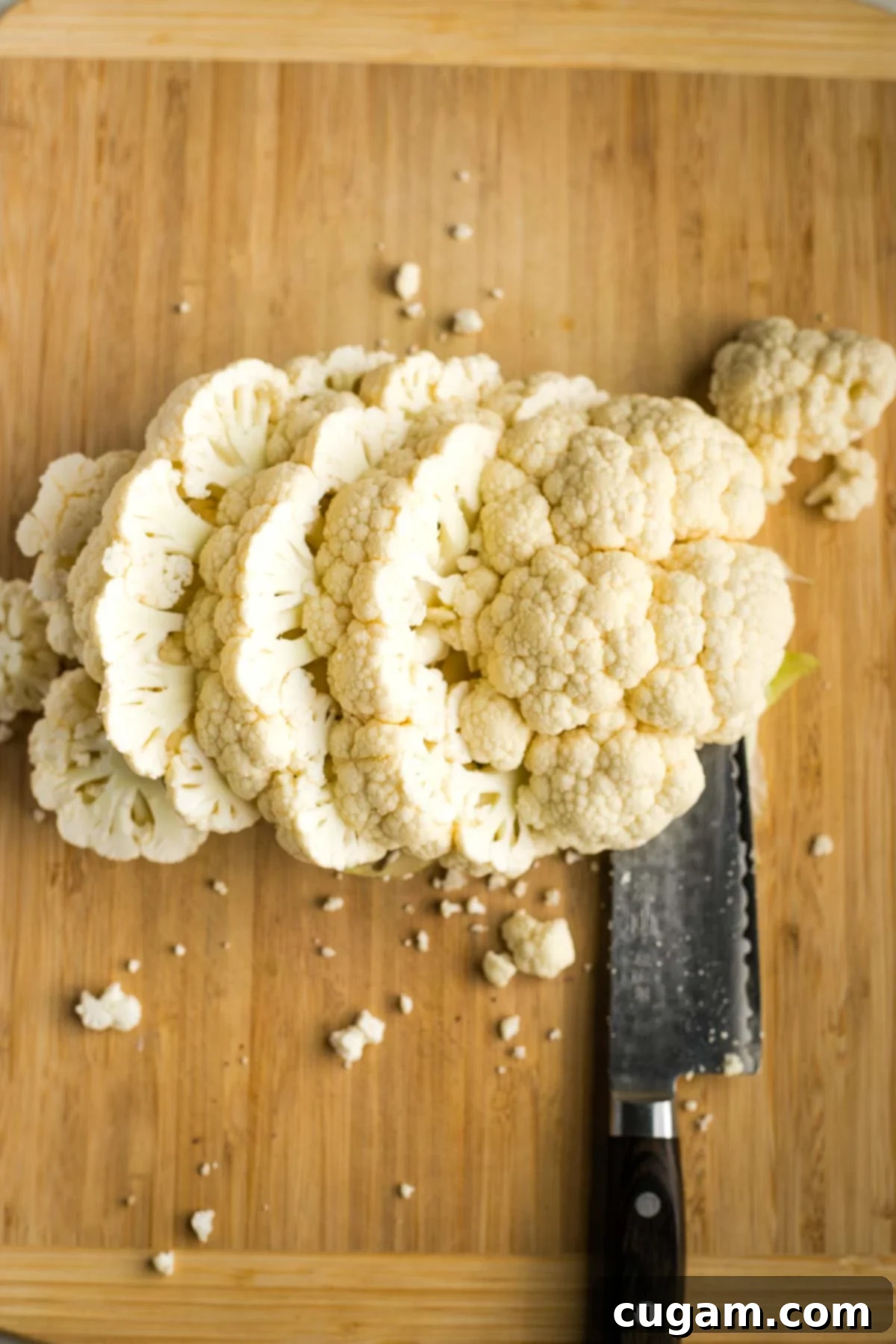 Several thick cauliflower steaks neatly arranged on a wooden cutting board, ready for seasoning.
