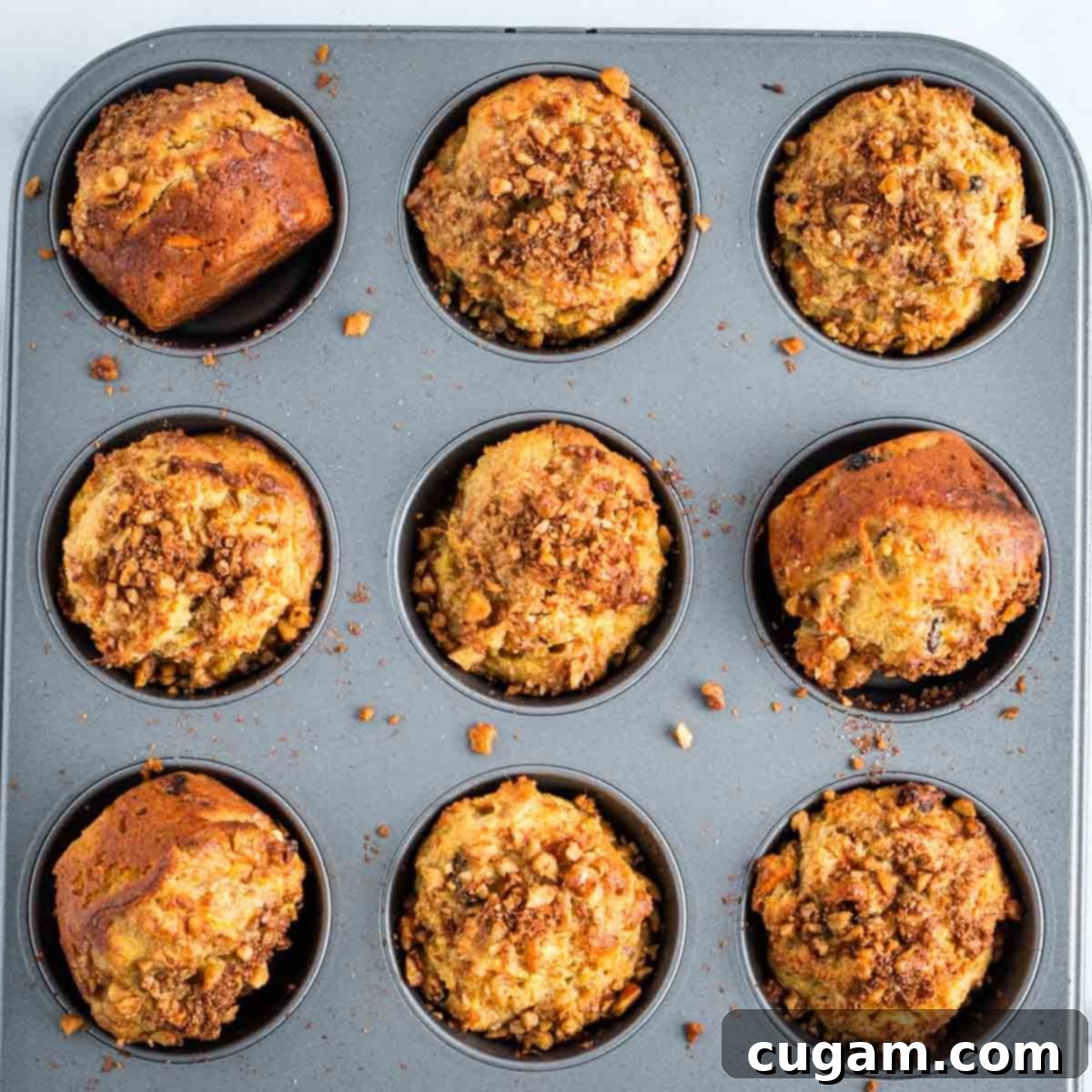 Baked carrot muffins with golden tops in a muffin tin.