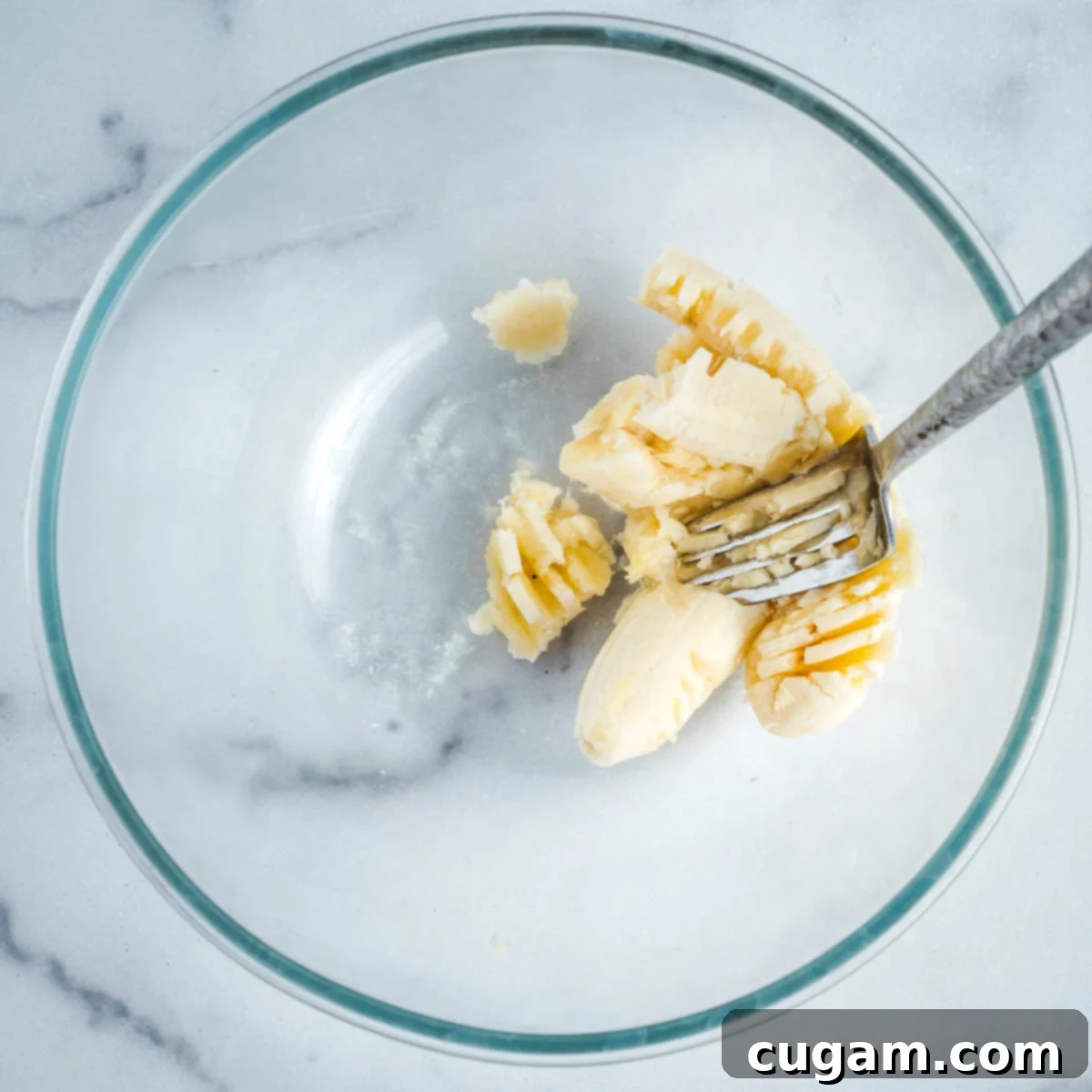 Mashing a ripe banana in a mixing bowl with a fork.