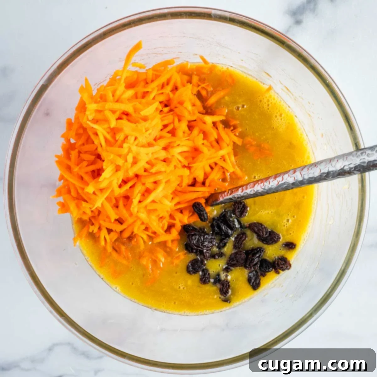 Adding shredded carrots and raisins to the wet mixture.