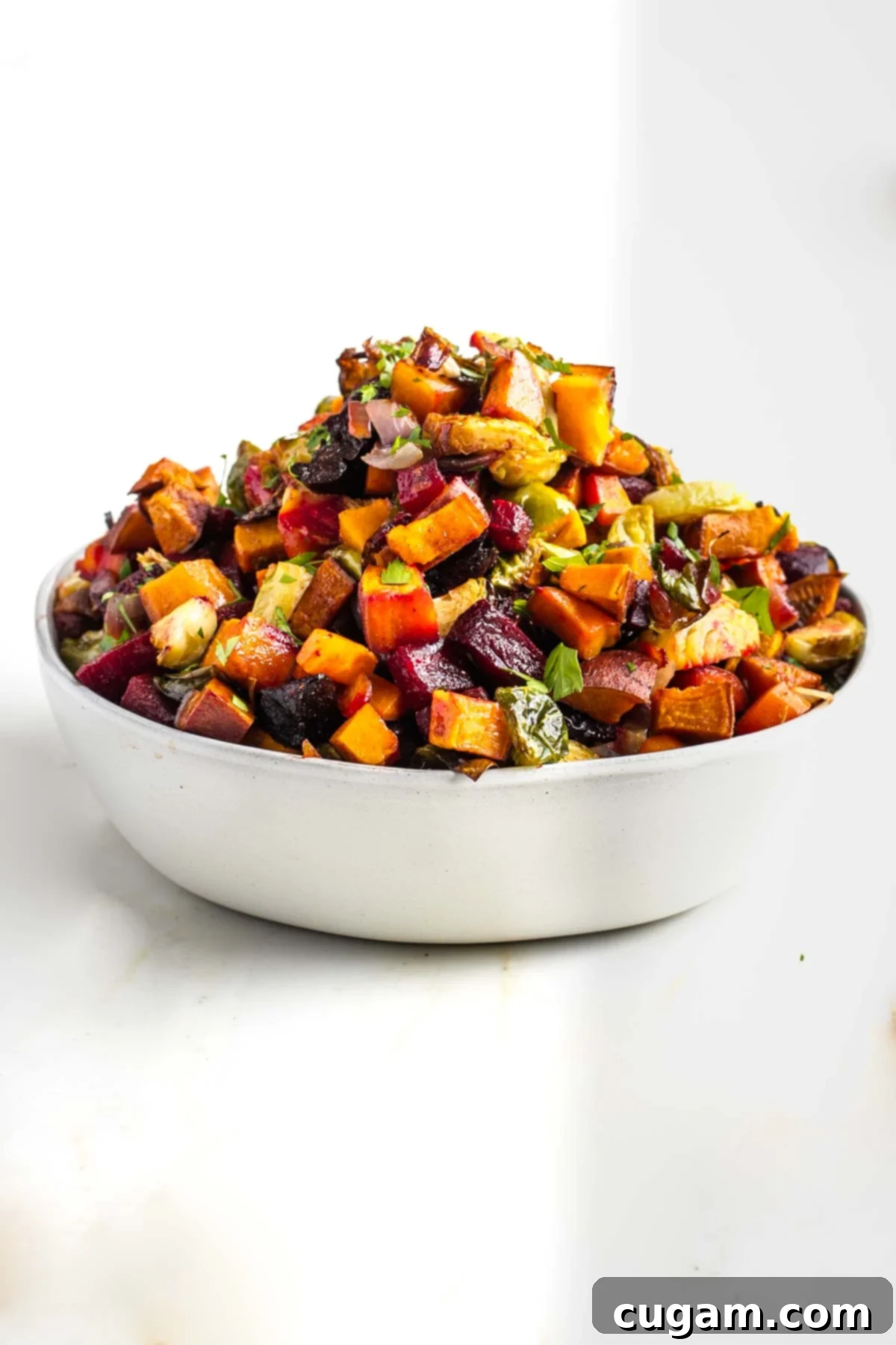 Bowl piled high with tzimmes, small cubes of colorful vegetables that have been roasted. 