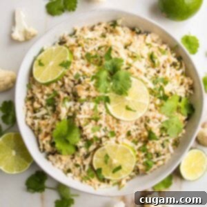 Effortless Stovetop Cauliflower Rice 13 Cauliflower Rice with lime slices and cilantro in a white, low shallow bowl.