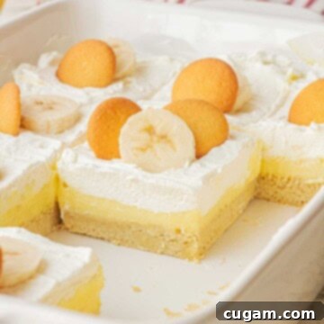 Baked slices of delicious banana cream pie bars presented in a white ceramic pan, garnished beautifully.
