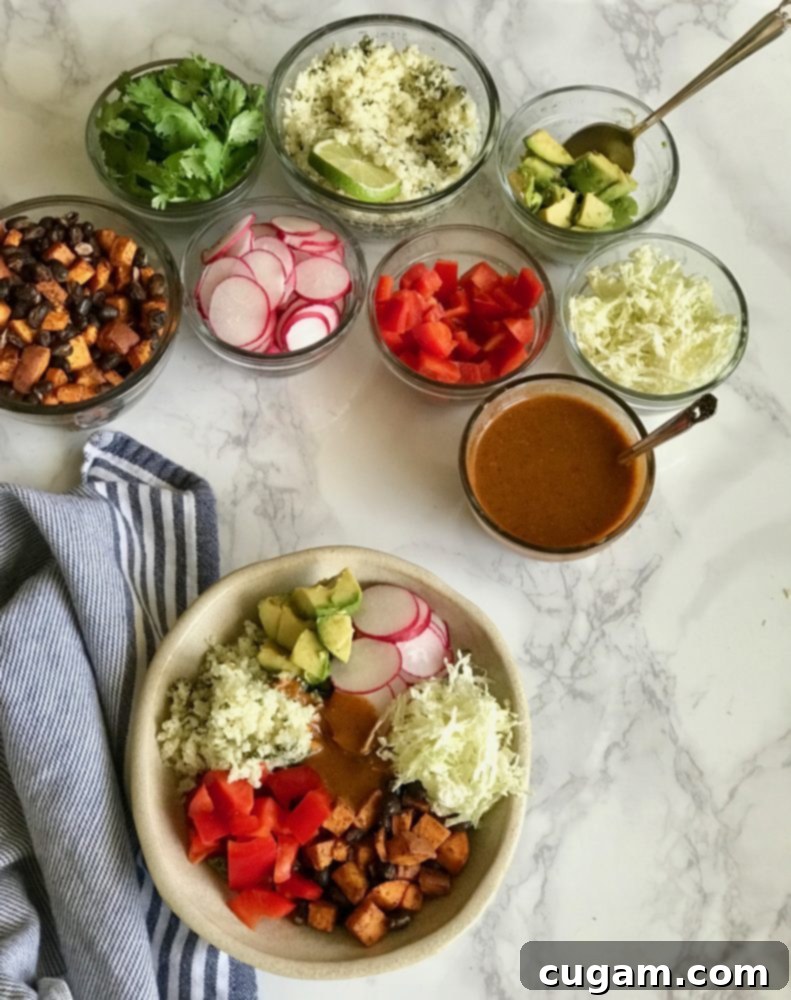 A vibrant enchilada bowl featuring roasted sweet potatoes, black beans, fresh veggies, and rich red enchilada sauce, surrounded by small dishes of ingredients for a customizable experience.