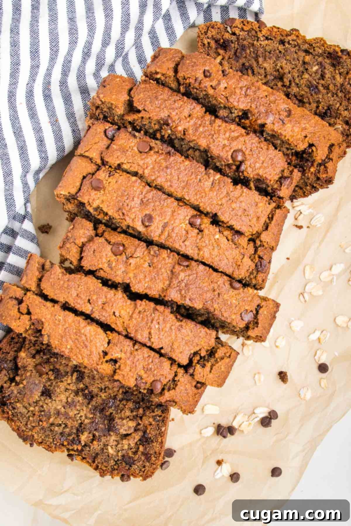 Thick slices of chocolate chip banana bread on a piece of parchment with a kitchen towel off to the side.