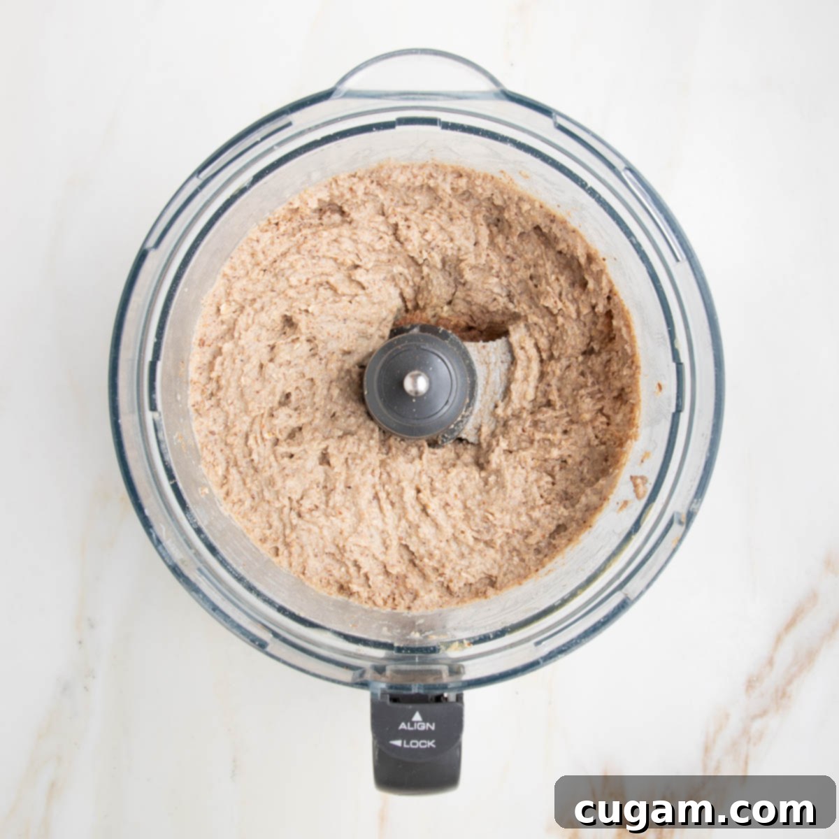 light brown banana bread batter in the bowl of a food processor