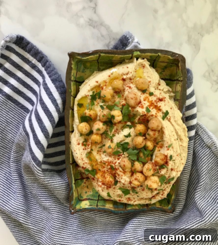 Hummus in a dish topped with chickpeas, paprika and chopped parsley.