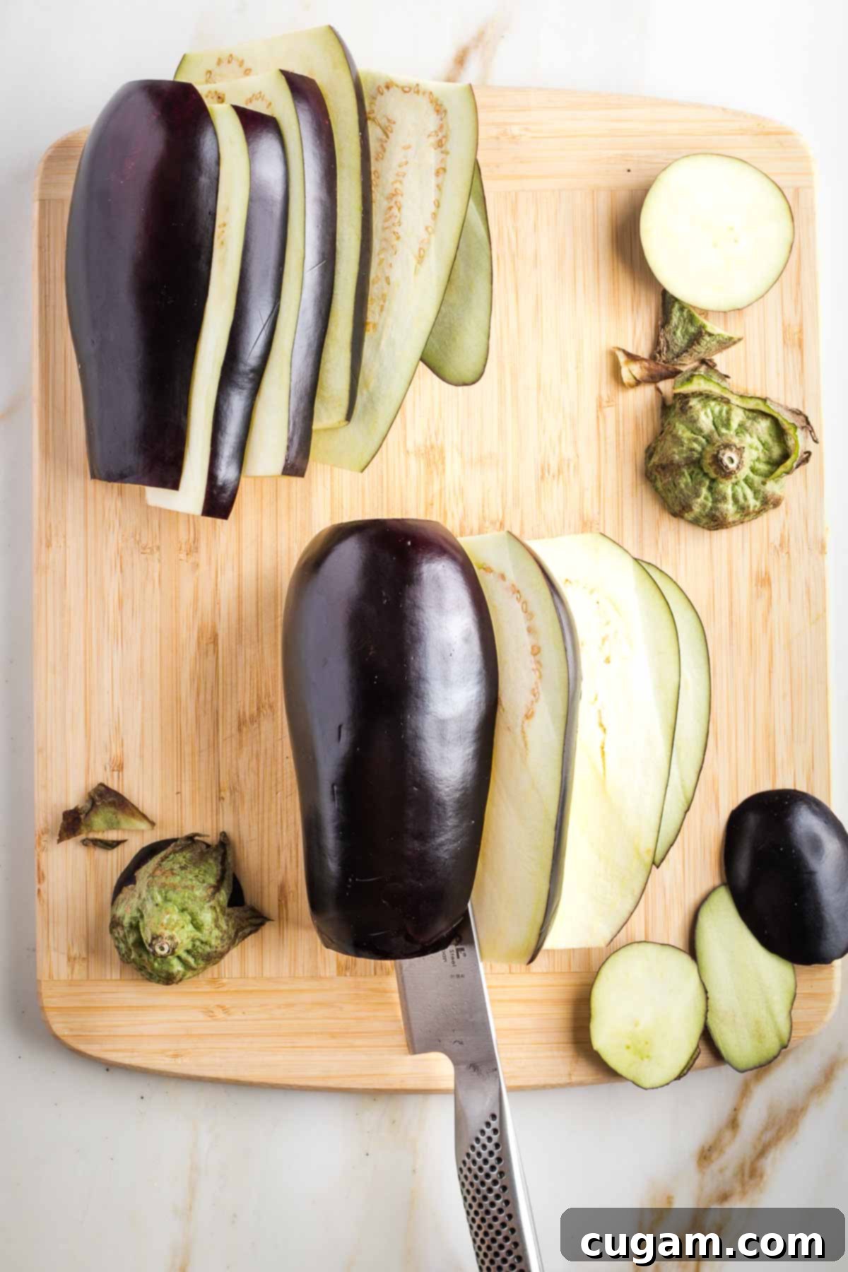 Showing how to make lengthwise slices in eggplant that had tops and bottoms already cut off.