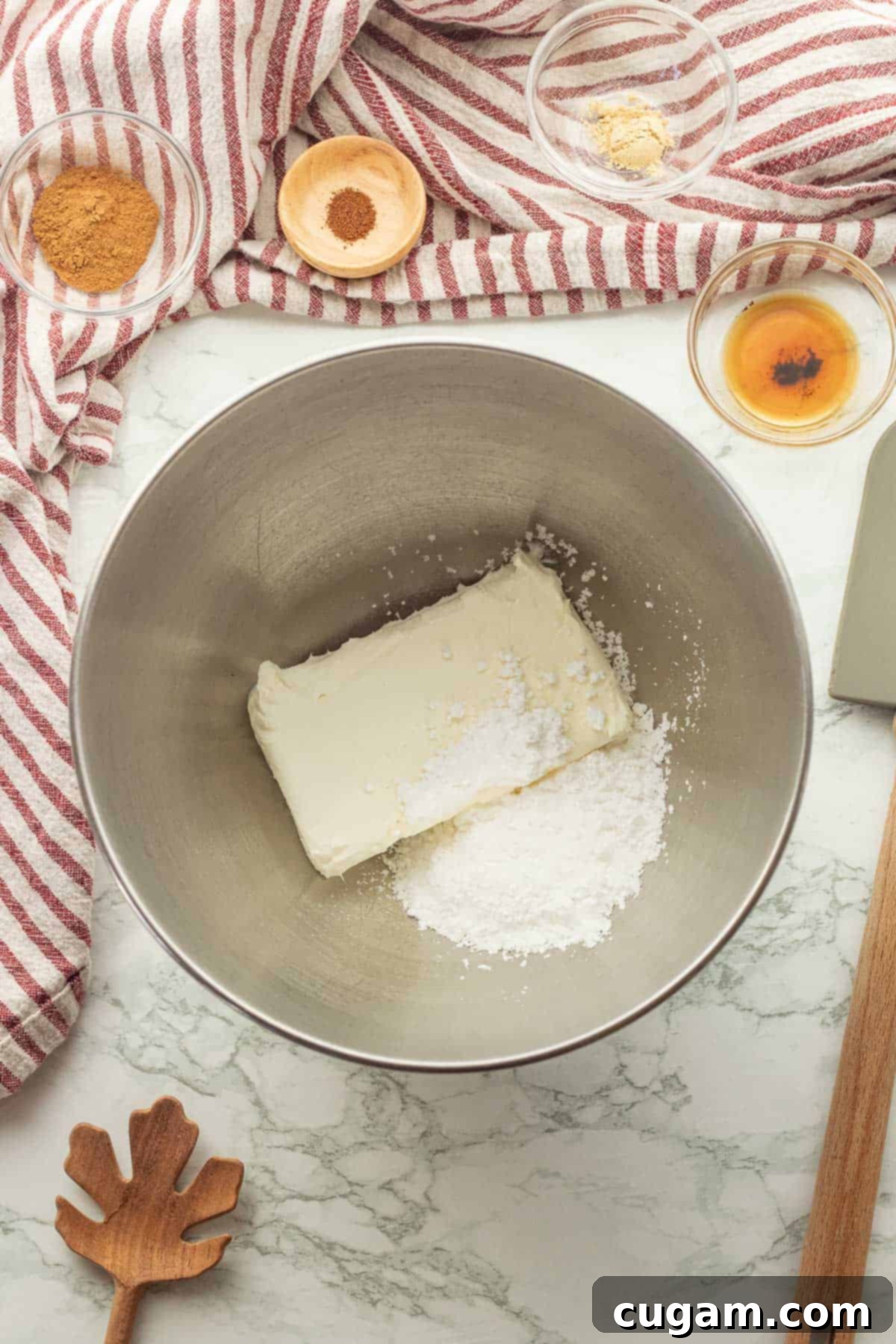 Irresistible Pumpkin Cream Cheese Dip 4 Softened cream cheese and powdered sugar expertly combined in a metal bowl, resting on a elegant marble countertop, ready for the next step of the dip.