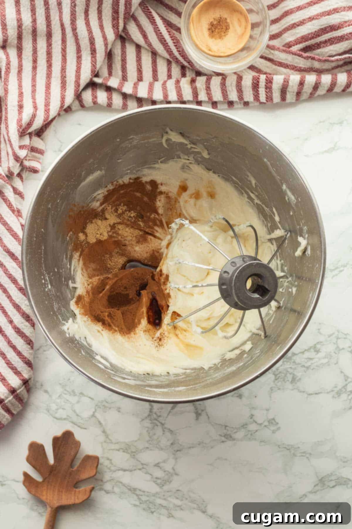 Irresistible Pumpkin Cream Cheese Dip 5 A whisk gracefully blending warm spices and vanilla extract into the creamy, whipped cream cheese mixture, ensuring an even distribution of flavor.