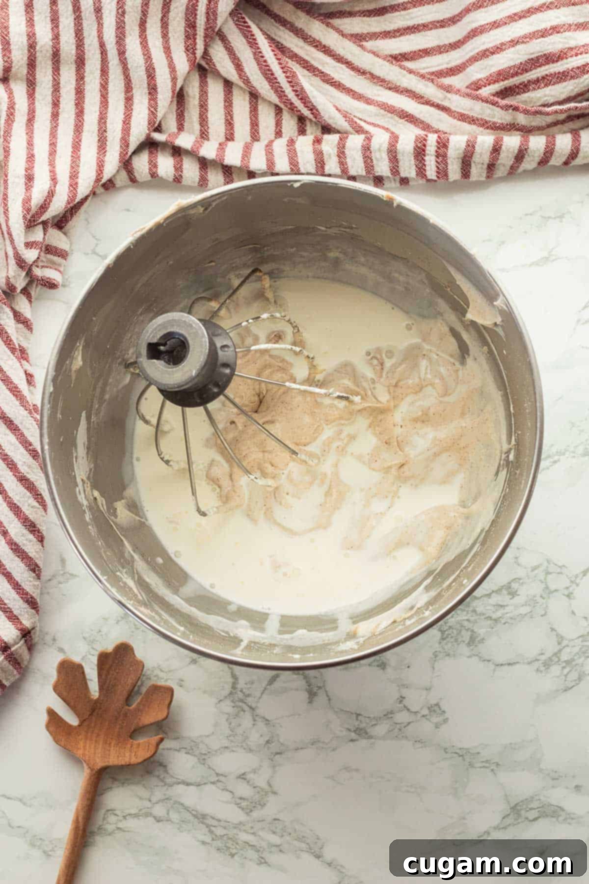 Irresistible Pumpkin Cream Cheese Dip 6 A steady stream of cold heavy cream being poured into the fluffy cream cheese base, an essential step in creating the light and airy pumpkin dip.