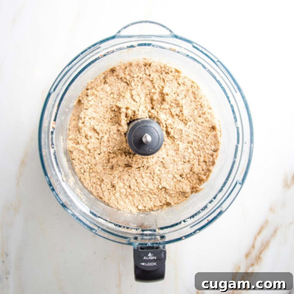 Crust of crumble bars inside a food processor...it looks pasty and beige with some texture to it, ready for assembly.