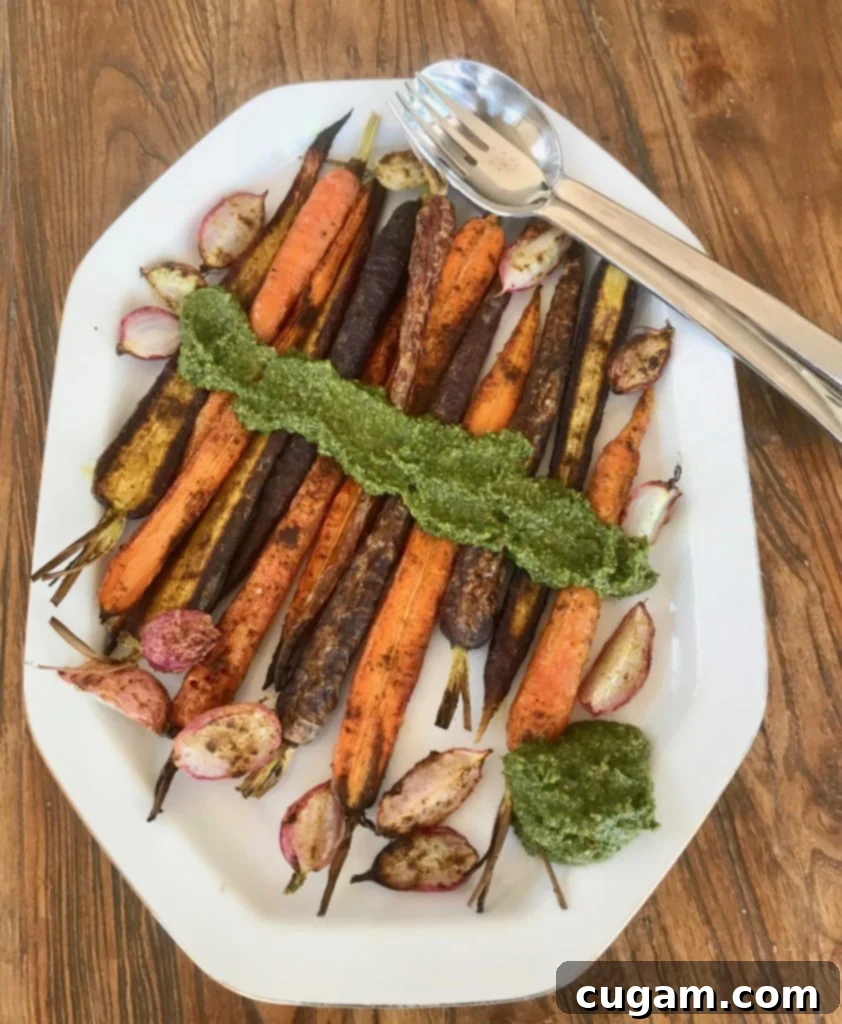Roasted vegetables generously coated with bright green carrot top pesto, served as a delicious and healthy meal.