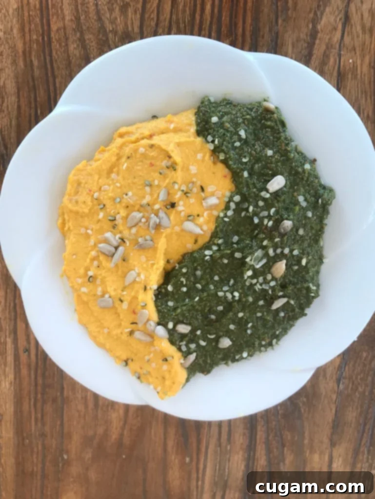 Two separate bowls, one with creamy hummus and the other with vibrant carrot top pesto, representing a harmonious blend of flavors.