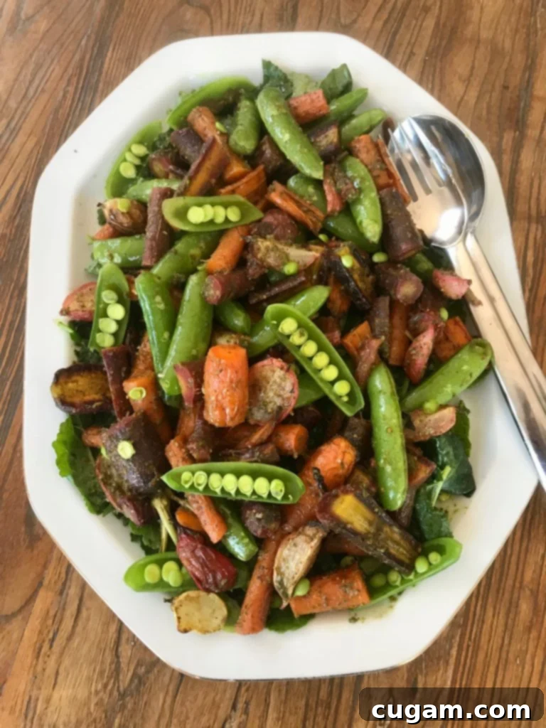 A colorful serving of roasted vegetables and pesto, beautifully presented on a bed of fresh baby kale.