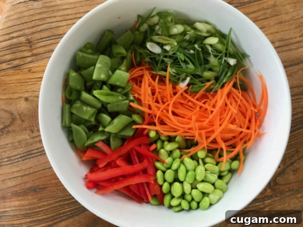 bowl full of prepped veggies:  edamame, carrots, red peppers, scallions, snap peas