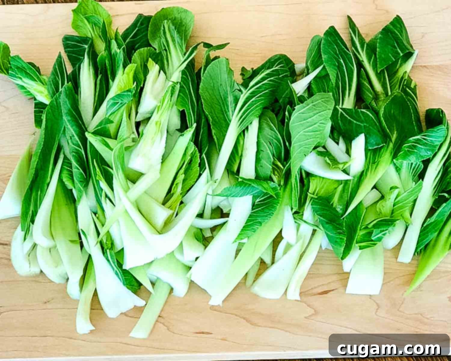 Aromatic Ginger Scallion Bok Choy 5 Leaves of baby bok choy spread out on a cutting board.