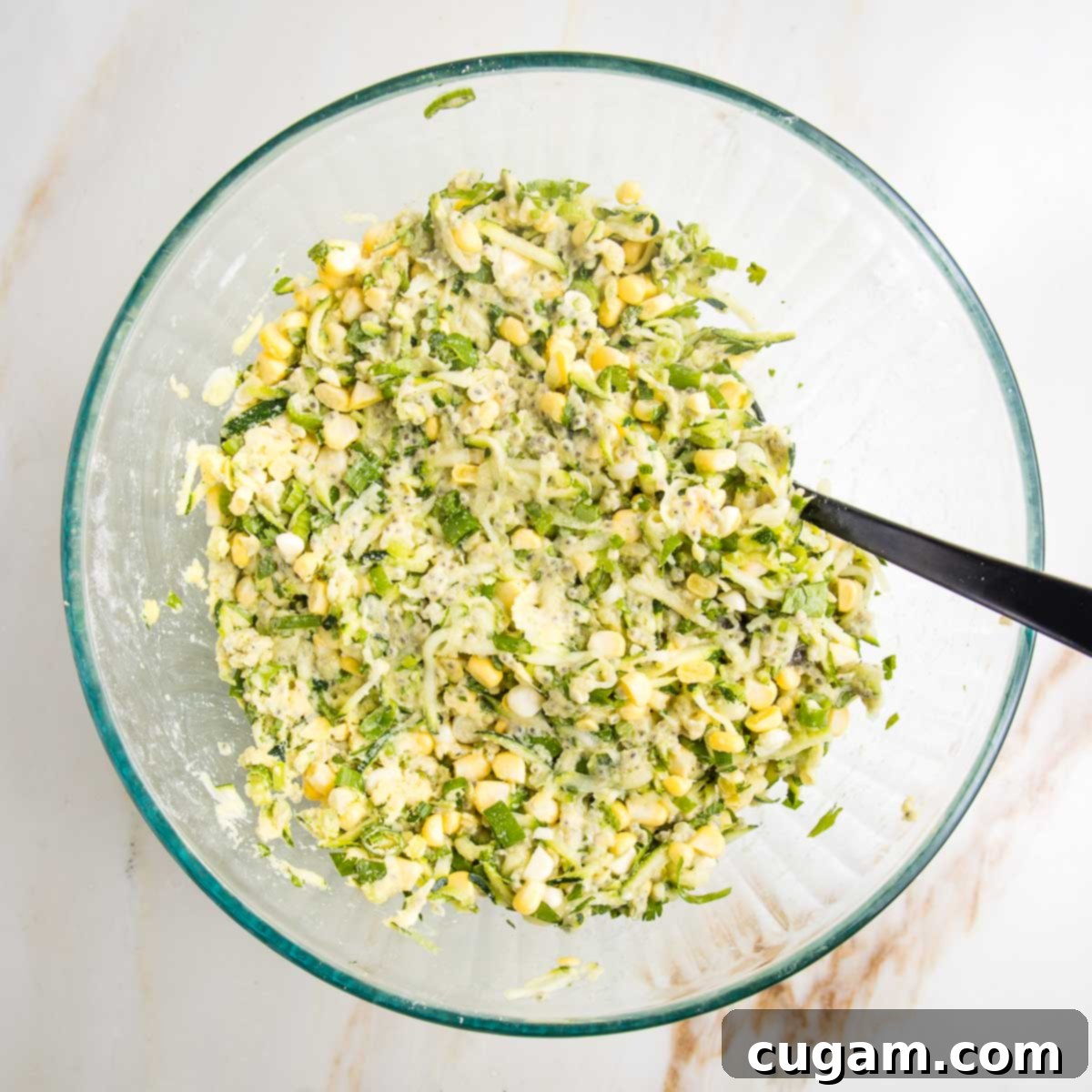Batter for vegetable fritters in a large glass bowl.