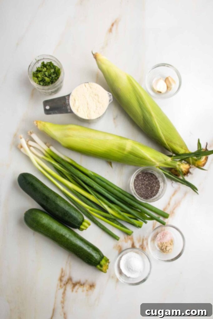 Ingredients for corn and zucchini fritters: zucchini, scallions, fresh corn, corn meal, chopped cilantro, chia seeds, baking powder, salt, pepper, garlic.