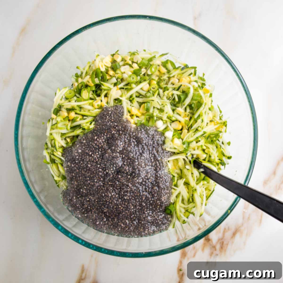 Shredded zucchini plus corn mixture with 2 chia eggs poured on top in a large glass bowl.